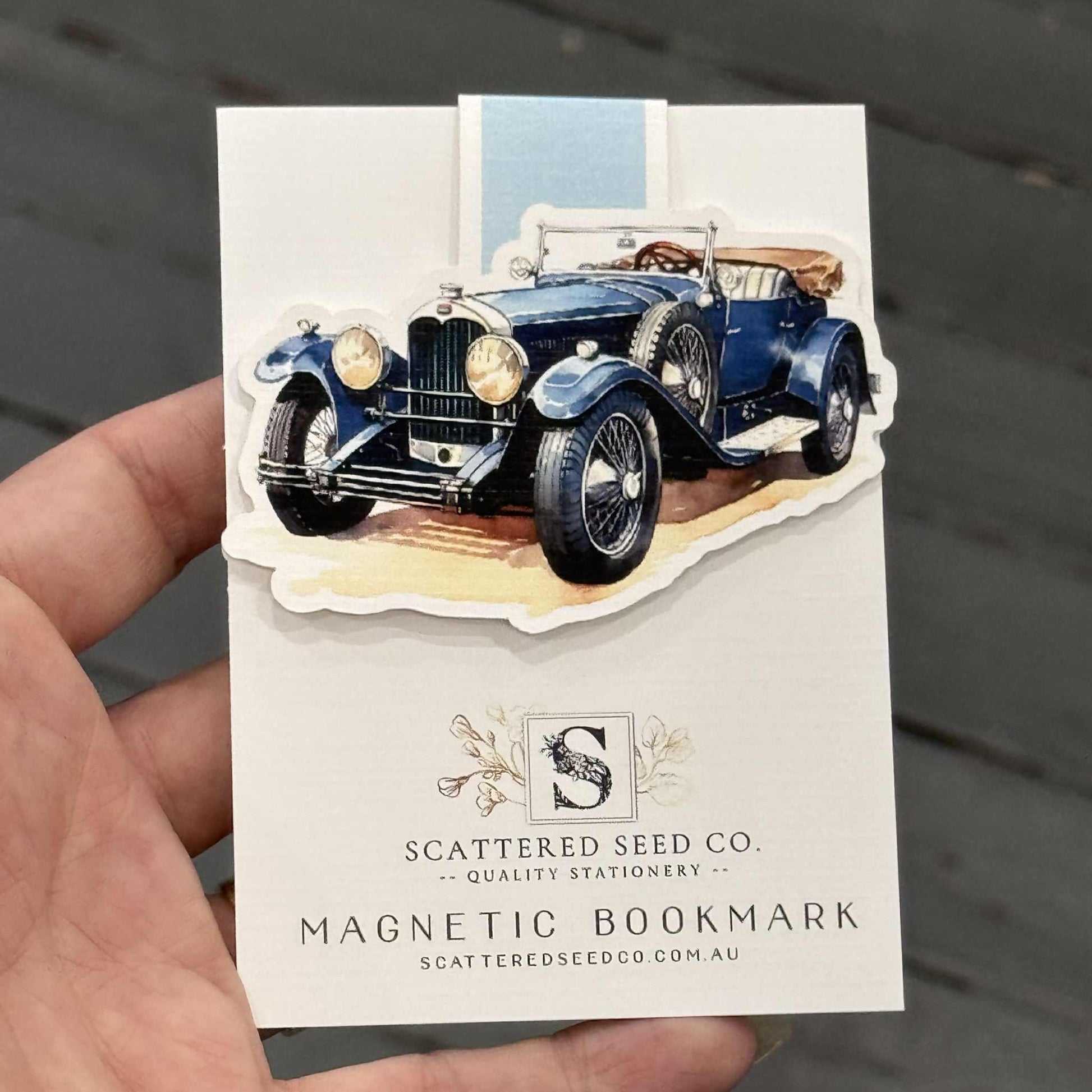 Hand holding a magnetic bookmark with a vintage car design - The Book Keeper and Co