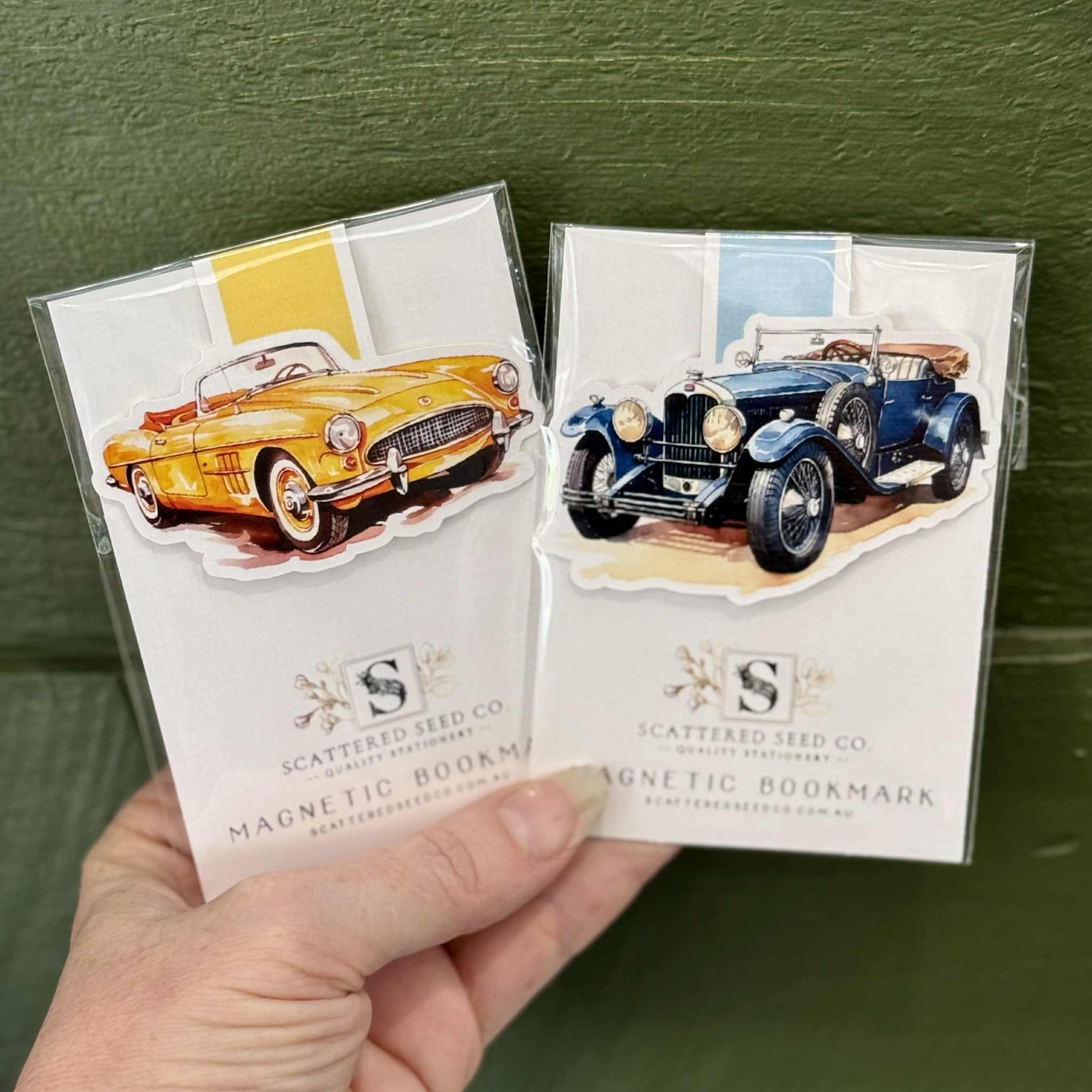 Two vintage car-themed magnetic bookmarks held against a green background - The Book Keeper & Co
