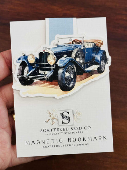 Magnetic bookmark with vintage car design held by a hand on a wooden surface - The Book Keeper & Co