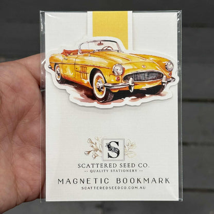 Magnetic bookmark with a yellow vintage car design held by a hand. - The Book Keeper and Co
