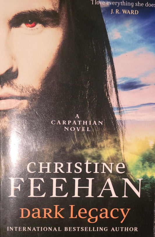 Book cover of 'Dark Legacy' by Christine Feehan featuring a man with red eyes and a scenic background.
