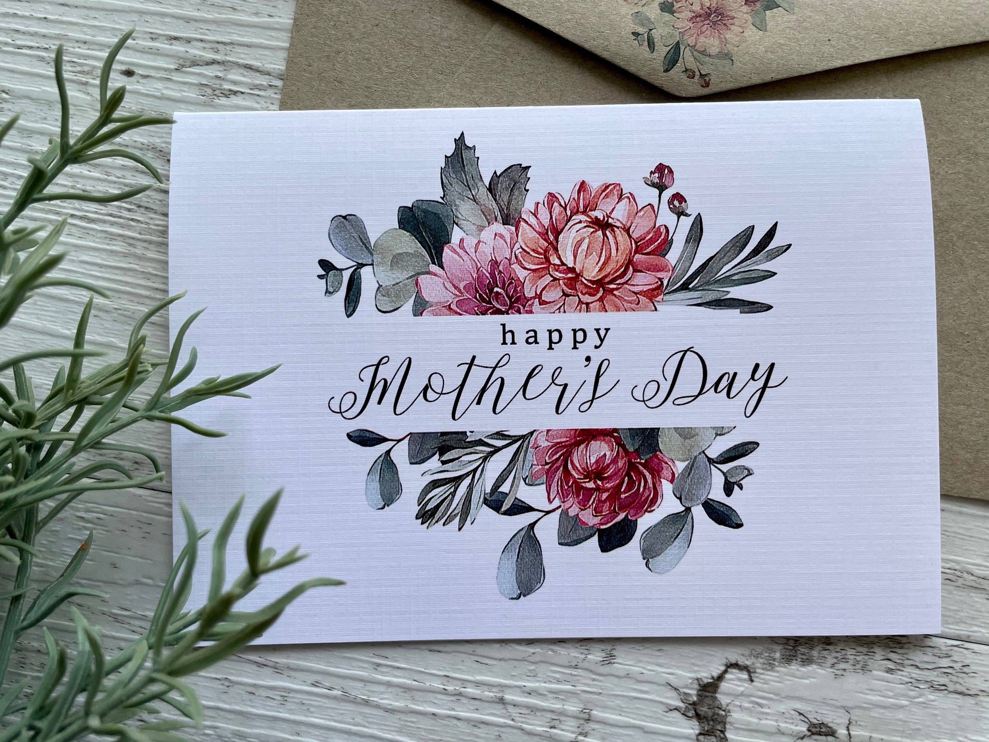 Greeting card with floral design and 'Happy Mother's Day' text on a wooden surface.