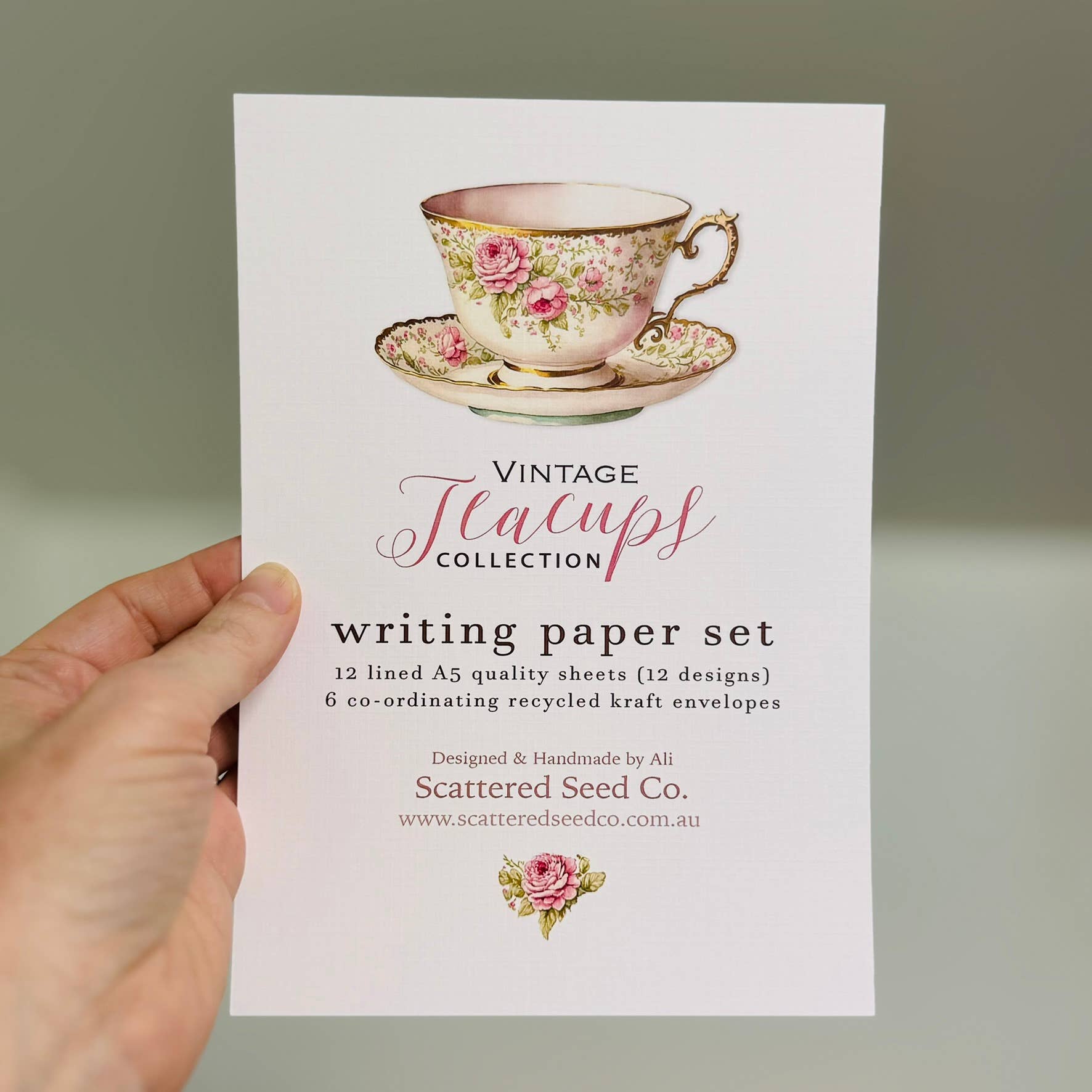 Hand holding a card with a vintage teacup design and product details.