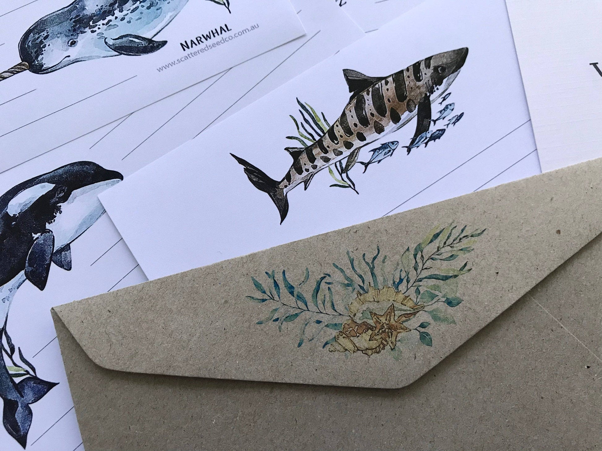 Kraft paper envelope with floral design on a white background with whale illustrations.