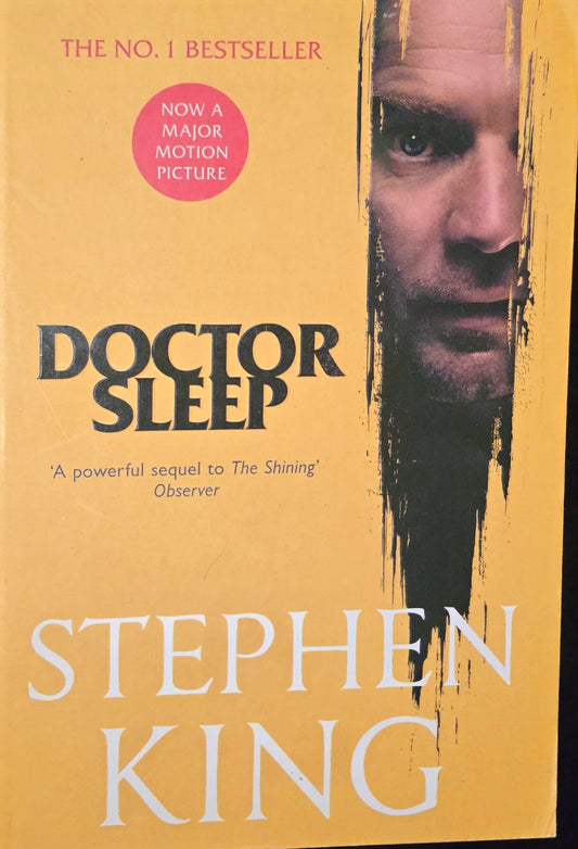 Book cover of 'Doctor Sleep' by Stephen King with a yellow background and a face peeking from the side.