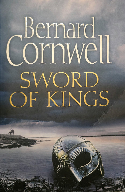 Book cover of 'Sword of Kings' by Bernard Cornwell with a helmet and landscape.