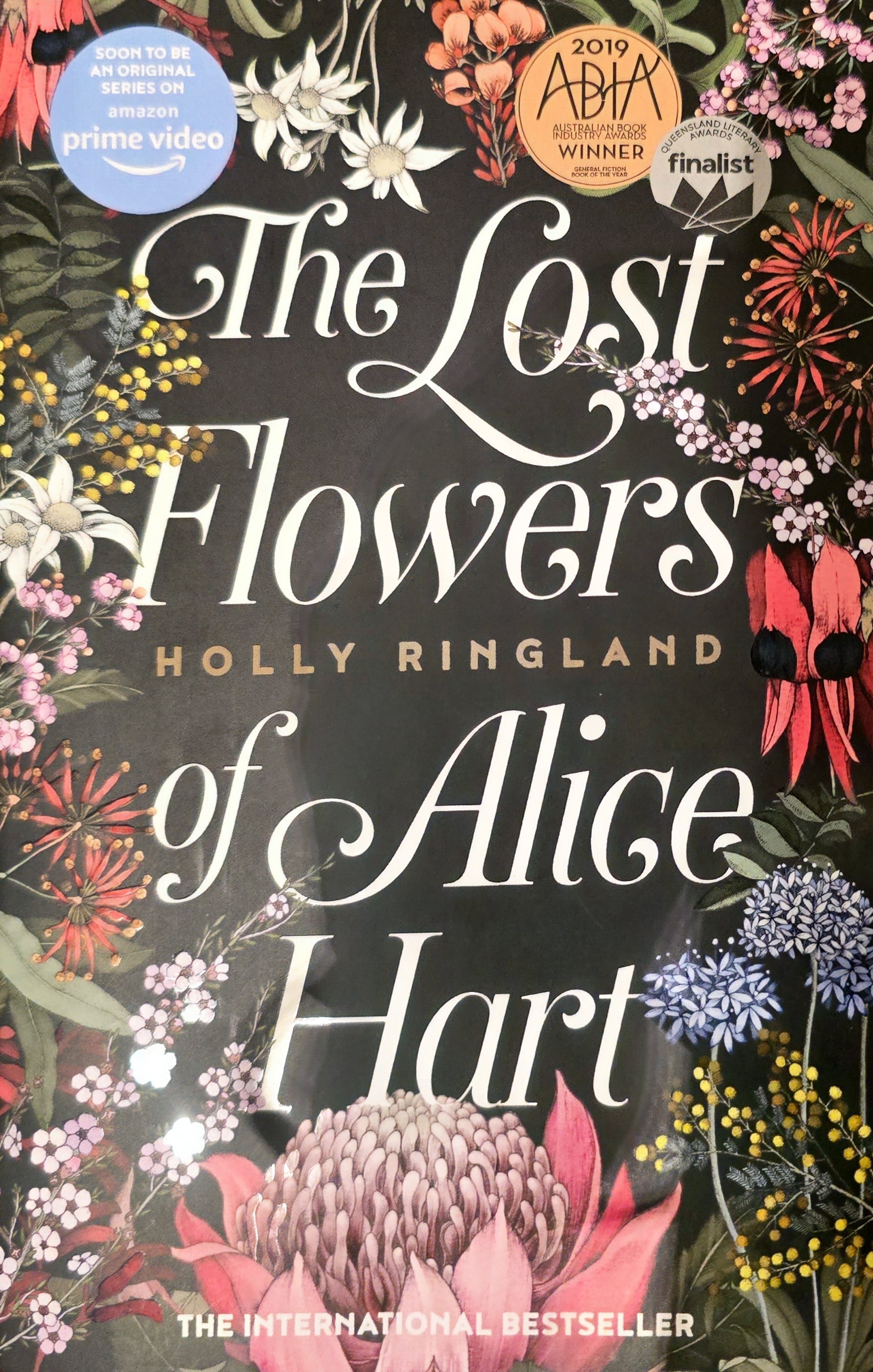 Book cover of 'The Lost Flowers of Alice Hart' with floral design and awards on a black background