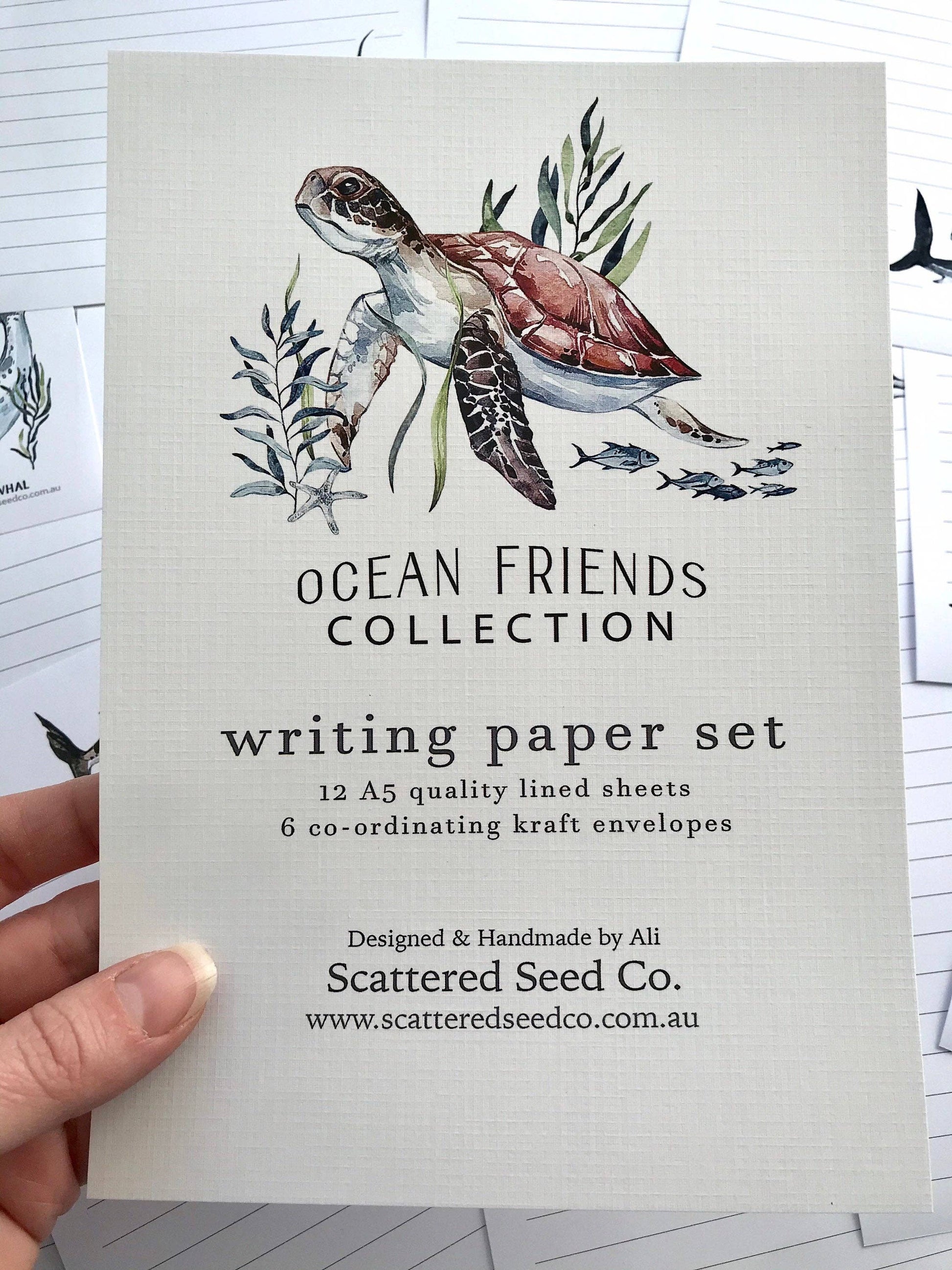 Writing paper set with turtle illustration and 'Ocean Friends Collection' text, held by a hand.