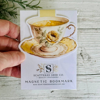 Magnetic bookmark with tea cup design held by a hand on a wooden surface - The Book Keeper and Co