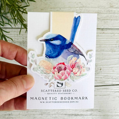 Magnetic bookmark with a blue bird design held by a hand on a wooden surface - The Book Keeper and Co